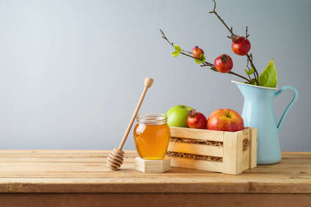 Still life composition for Rosh Hashanah holiday. Honey jar and apples in wooden box on table backgroundの写真素材
