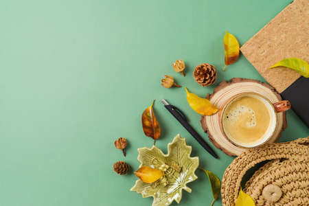 Coffeee cup, planner, bag and autumn leaves on green background. Stylish boho table. Back to school concept. Top view, flat layの写真素材