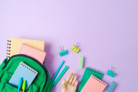 Back to school  concept with green backpack and school supplies on purple background. Top view, flat layの写真素材