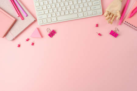 Feminine pink desk with notebook and computer keyboard. Background for Back to school concept. Top view, flat layの写真素材