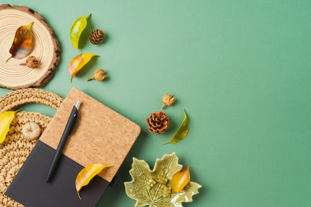 Stylish boho desk with planner, bag and autumn leaves on green background. Back to school concept. Top view, flat layの写真素材