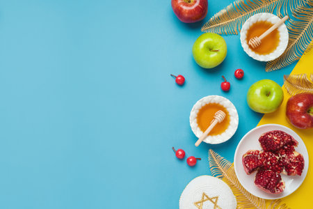 Jewish holiday Rosh Hashana banner design with honey, apple and pomegranate over blue background. Top view, flat layの写真素材
