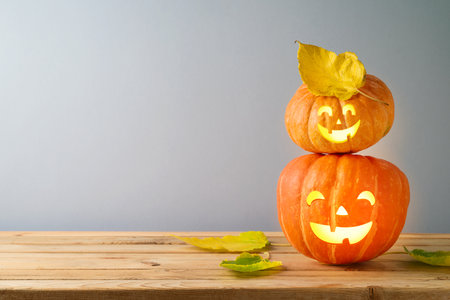Halloween jack o lantern pumpkin decoration on wooden table over gray wall backgroundの写真素材
