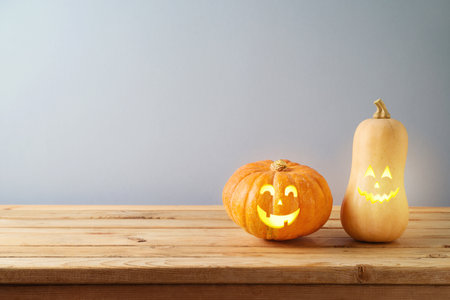 Halloween jack o lantern pumpkin decoration on wooden table over gray wall backgroundの写真素材
