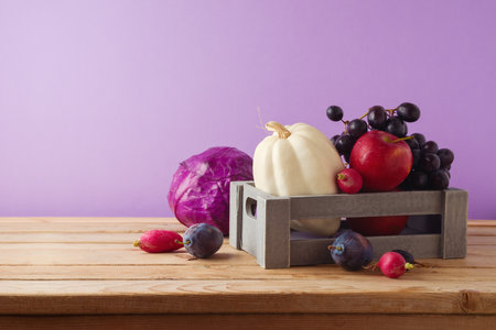 Healthy harvest concept.  Pumpkin, apple, grapes and vegetables in wooden box on table.  Autumn still lifeの写真素材
