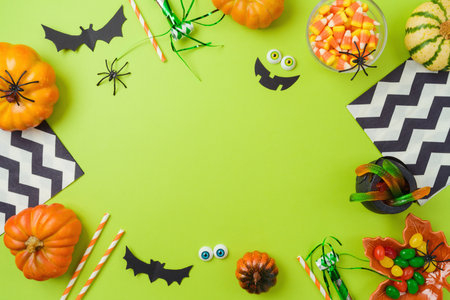 Halloween party frame border design. Pumpkin, candy and decorations on green background. Top view, flat layの写真素材