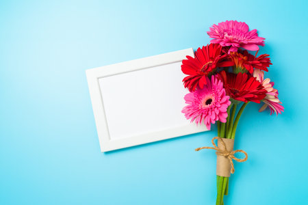 Hello spring concept background with flowers and frame mock up on blue background. Top view, flat layの写真素材