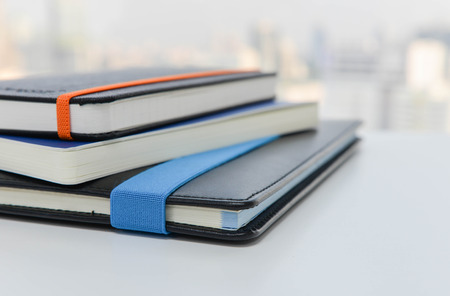 Stack of books on the white table with blur city view backgroundの写真素材