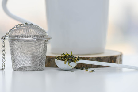Dry tea leaves in a teaspoon with Tea strainer and cupの写真素材