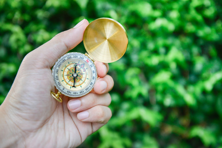 Human hand hold the compass with green nature backgroundの写真素材