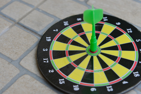 Close up green darts arrow on the target center of dartboar for business goal concept