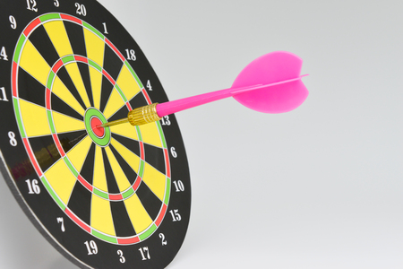 Close up pink darts arrow on the target center of dartboard with white background for business goal conceptの写真素材