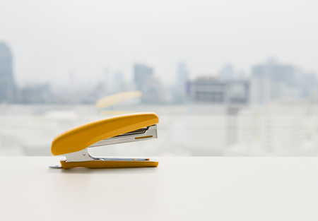 Yellow stapler on the white desk - office stationaryの写真素材
