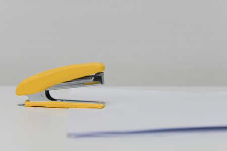 Yellow stapler with white paper for office stationaryの写真素材