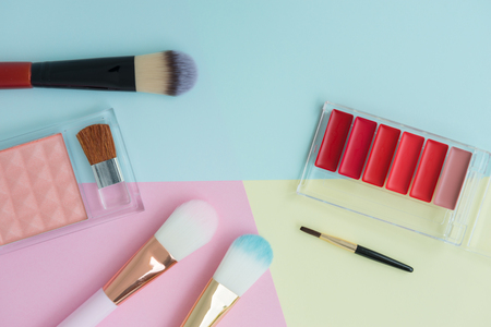 Flat lay creative concept of female decorative cosmetic for brush on, cheek brush and lipstick palette on the colorful background with copy spaceの写真素材