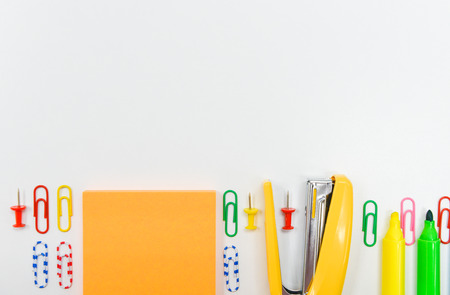 flat lay of office or school stationary including stapler, paper note, paperclip, pen and...