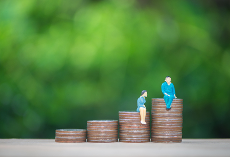 Mini human model standing with the growing coins stack with green nature background for business and finance conceptの写真素材