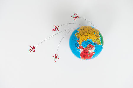 Globe model with air plane paper clip flying circle  on the white background for transport and travel conceptの写真素材
