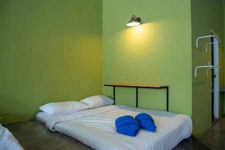 White mattress and towel in the hostel resort room with green wall for vacationの写真素材