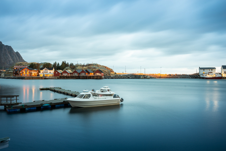 Long exposure of dock with speed boat and fishing rorbuer house village in Lofoten island Hamnoy Norwayの写真素材