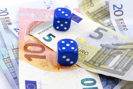 Photographed two blue gambling dices and lots of money on a black table.の写真素材