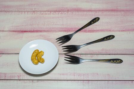 Corn snacks in a small plate and three forks.