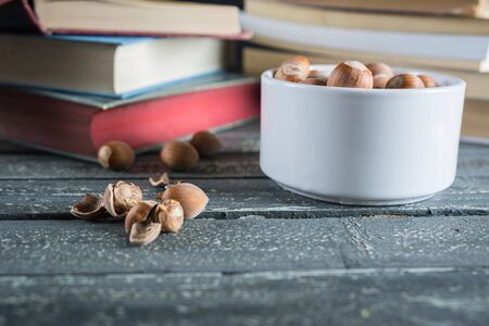 Lots of books and hazelnuts on a wooden table.の写真素材