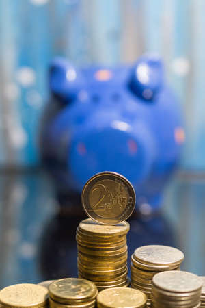 Euro coins with a lot of stacked coins and piggy bank in the background.の写真素材