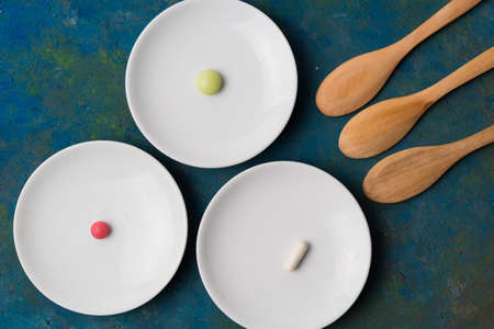 Tablets in white plates and wooden spoons on the table.