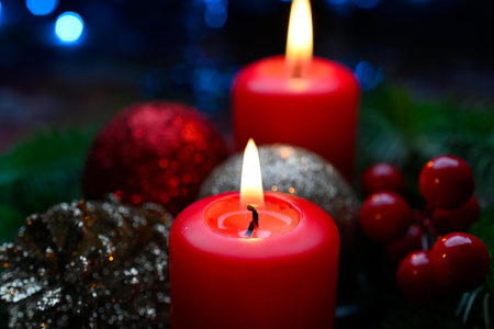 Lighted red candles surrounded by holiday decorations.の写真素材