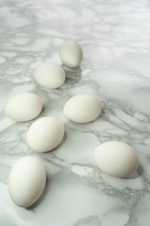 selective focus, fresh white chicken eggs in a scatter, on a marble light background with room for text.の写真素材