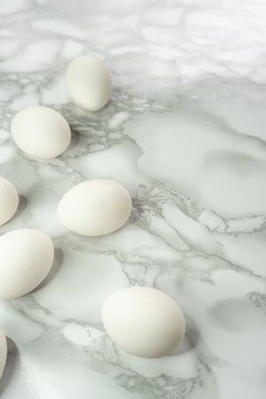 selective focus, fresh white chicken eggs in a scatter, on a marble light background with room for text.の写真素材