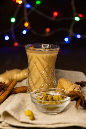 selective focus, Indian masala tea on the background of Christmas lights in a low key, with spices of cinnamon, anise and fresh gingerの写真素材
