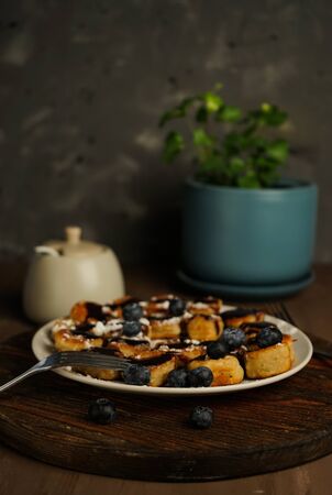 selective focus, curd fritter cubes with chocolate sauce, in home interior on dark backgroundの写真素材