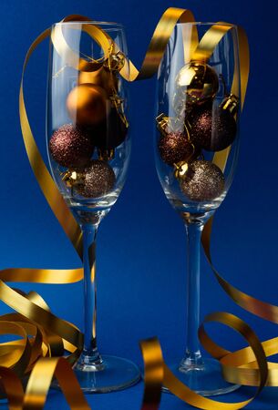new year champagne glasses on a trendy blue background, with Christmas balls and a gold ribbon, new year conceptの写真素材