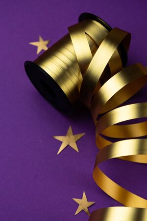selective focus, gold holiday ribbon on solid dark purple backgroundの写真素材