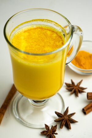 golden milk, with turmeric on a white background with cinnamon and star anise spicesの写真素材