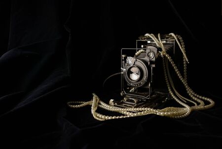 old retro film camera, black, on dark velvet fabric in low keyの写真素材