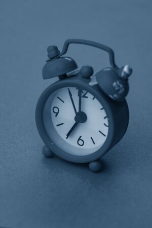 selective focus, small blue metal alarm clock with numbers in classic blue tintedの写真素材