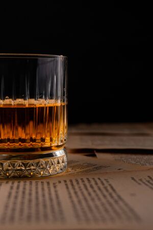 transparent glass of rye pure whiskey, on pages from books, on a dark backgroundの写真素材