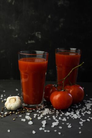 fresh tomato juice with pulp, with red tomatoes and coarse salt on a dark backgroundの写真素材