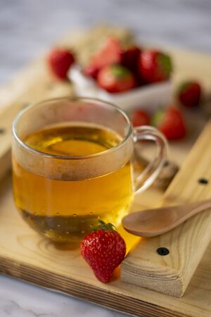 hot black tea with strawberry berries, on a wooden Boardの写真素材