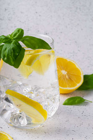 selective focus, pure refreshing water with lemon and Basil in a glass glass, on a light backgroundの写真素材