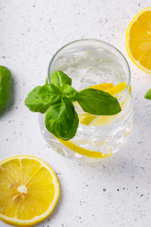 selective focus, pure refreshing water with lemon and Basil in a glass glass, on a light backgroundの写真素材