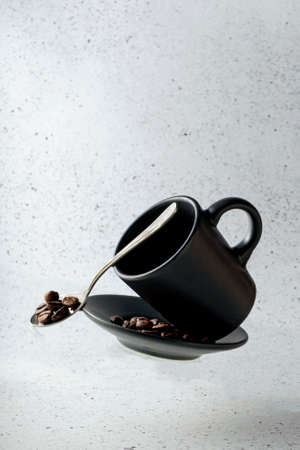 selective focus, flying espresso mug, with saucer and coffee beans on a light backgroundの写真素材