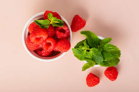 selective focus. fresh raspberries with a sprig of mint. in white fluted clay dishes on a soft pink...