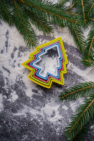selective focus, Christmas cookie cutter in the form of a Christmas tree, on the table with flour and fir branchesの写真素材