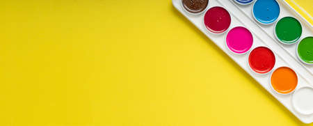 clean new palette of watercolors on a yellow paper background, copyspace