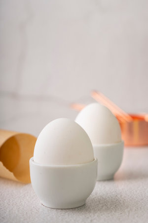 selective focus. fresh chicken egg in a white ceramic egg stand on a light background