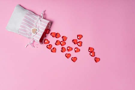selective focus. Valentine's day card. glass red hearts scattered from a beautiful cloth bag. the view from the top. pink backgroundの写真素材